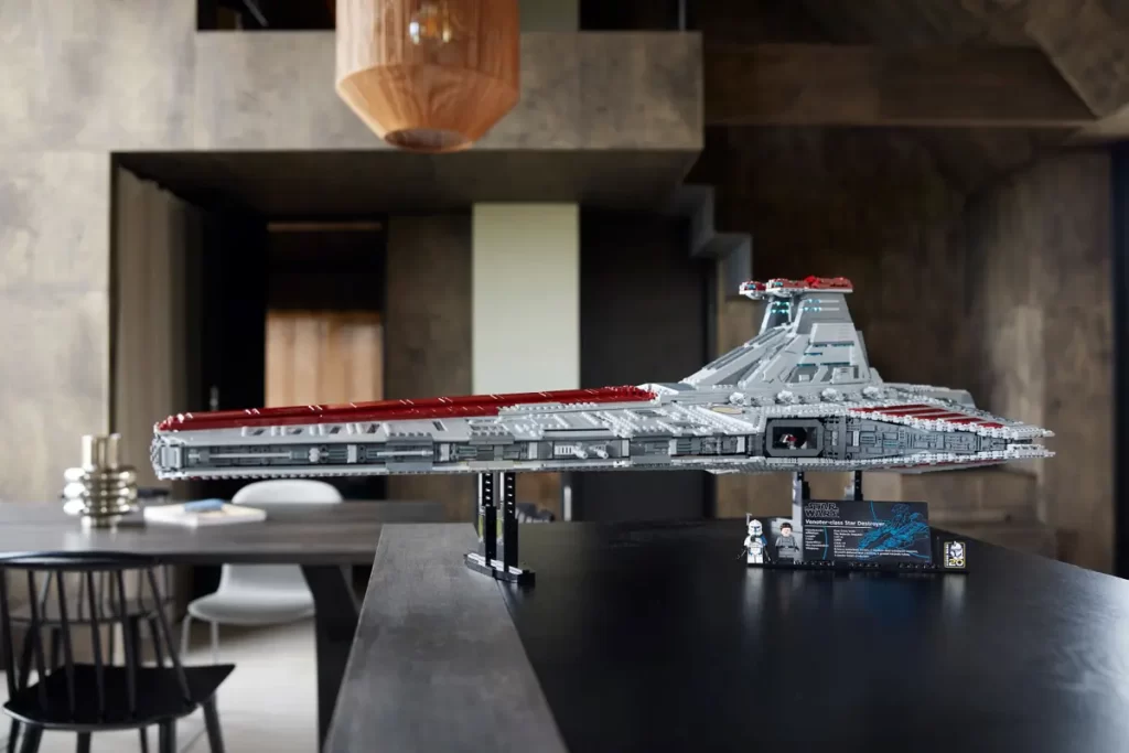 A large LEGO Revealed: UCS Star Wars™ Venator-Class Republic Attack Cruiser is displayed on a black table in a modern, stylish room with wooden accents and contemporary furniture.